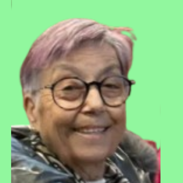 Anciana sonriente con gafas y cabello rosa sobre fondo verde.