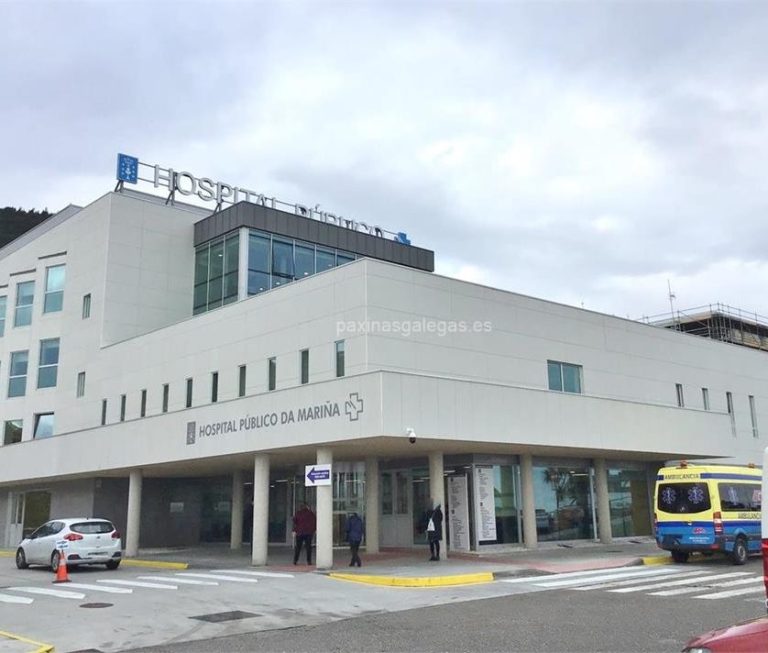 Edificio moderno de un hospital, con vehículos estacionados y gente en la entrada.